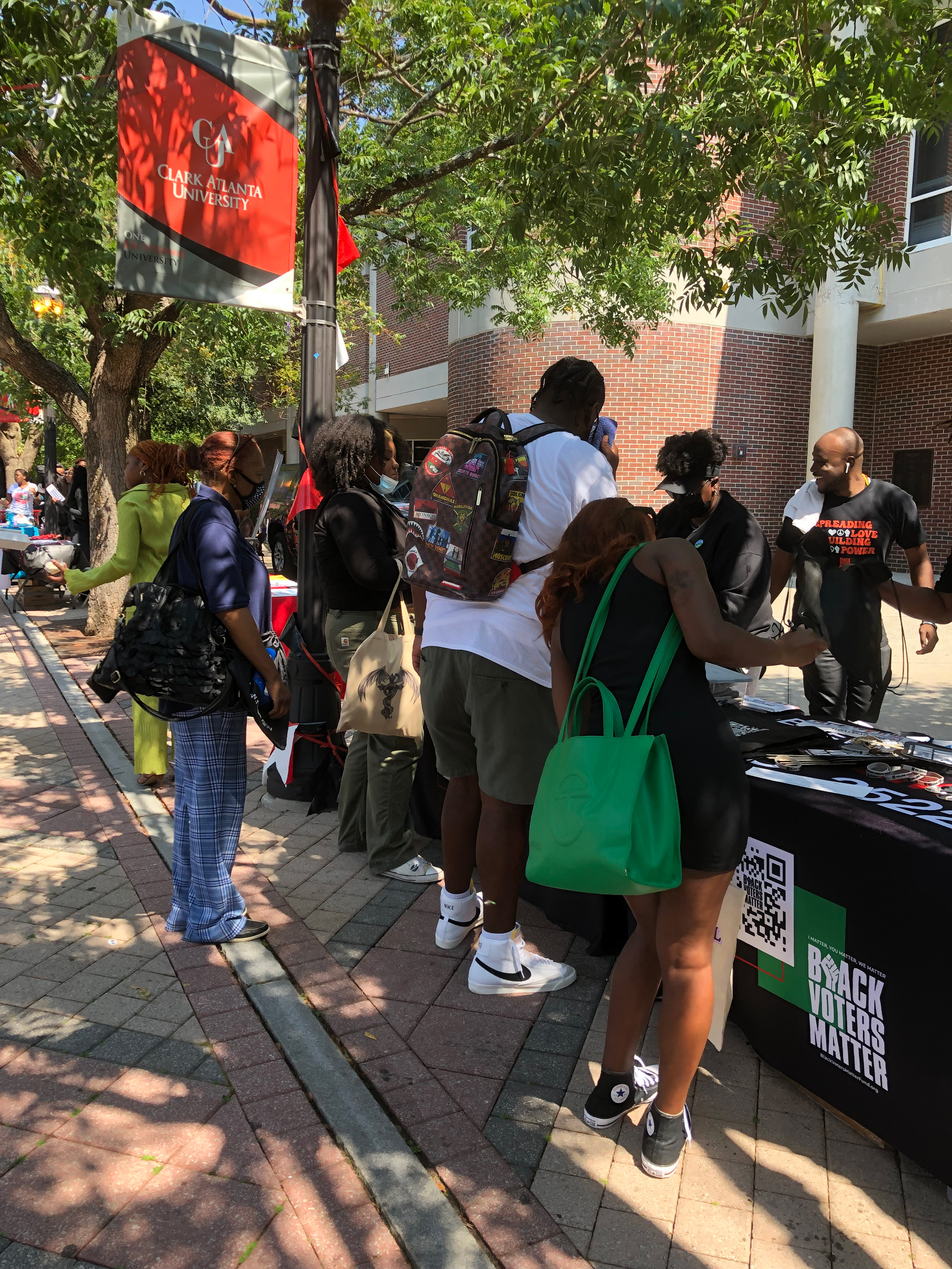 people standing next to a desk, registering to vote