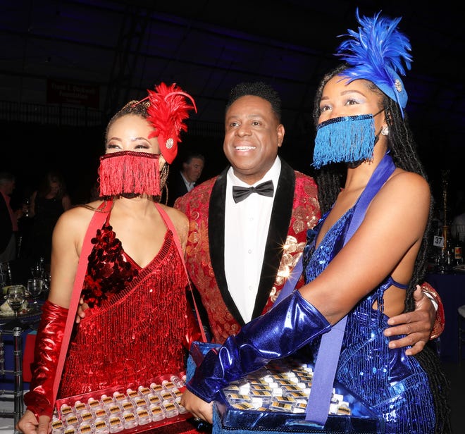 Flanking WBTT Founder and Artistic Director Nate Jacobs are the brilliantly costumed 'Cigarette Girls' who are a huge hit tonight! In red and hailing from New York is Delores McKenzie, and in blue is Atlanta's Katherine Taylor. Both girls are WBTT Artists and tonight they enjoy carrying trays of hand sanitizer which is both popular with the guests and a nod to our times. The Westcoast Black Theatre Troupe’s 22nd Anniversary Gala was held on Saturday, December 4, 2021 at the Circus Arts Conservatory’s Sailor Circus Arena in Sarasota, Florida. The event titled “A Night at the Savoy” turned the arena into a replication of New York City’s famous Harlem public, no-discrimination ballroom, The Savoy, which was in operation from 1926 – 1958. WBTT uses funds for education, artist development and a mentoring program geared toward underserved young people.
