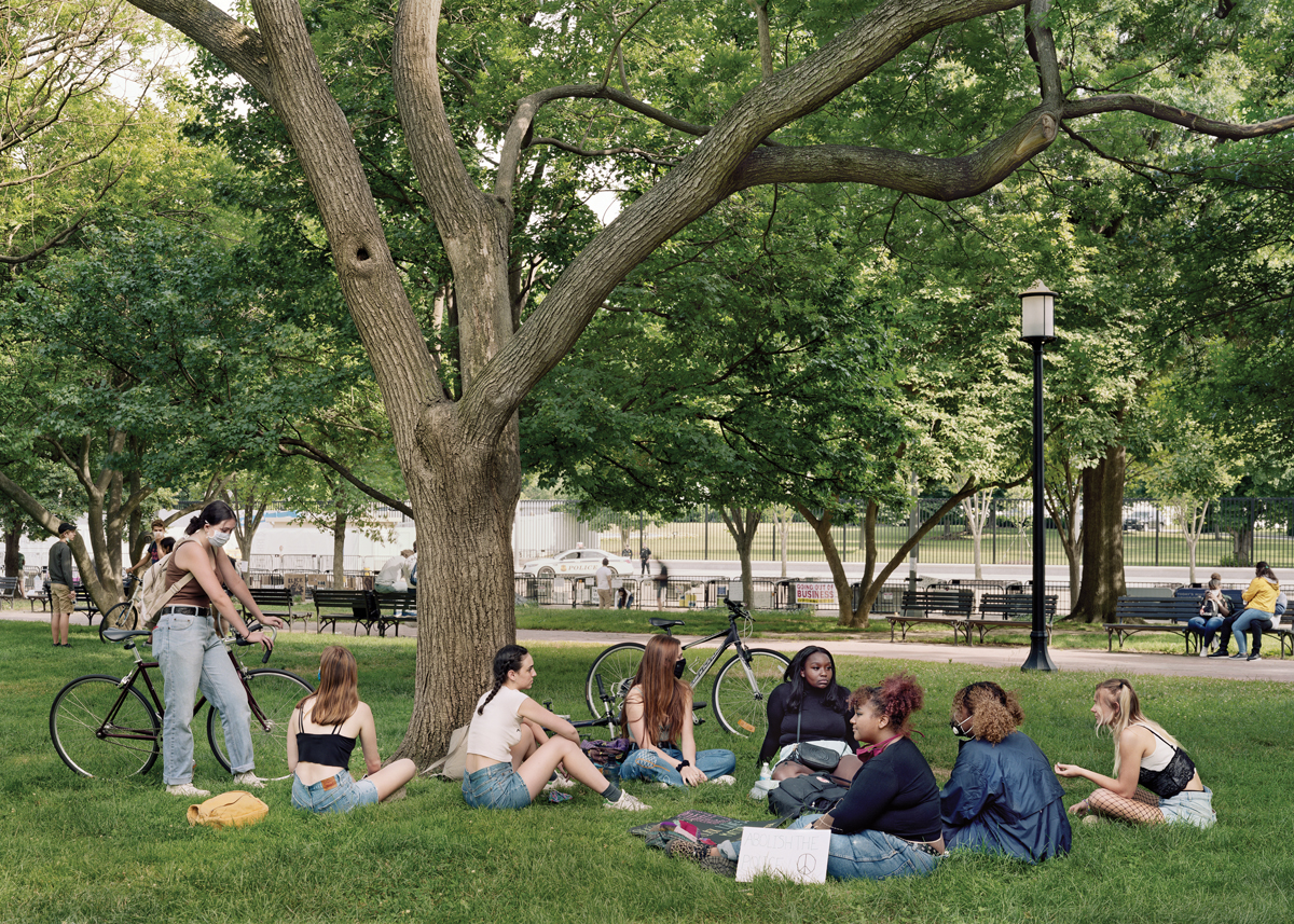 An-My Lê, High School Students after Black Lives Matter Protest, Lafayette Park, Washington, D.C., 2020, shows a group of young people sitting in a group in a park.