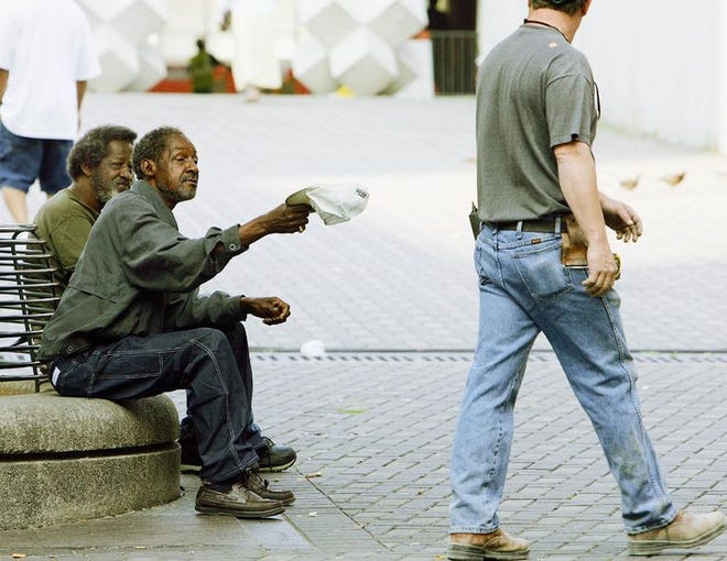 James Robert holds his hat out to a passerby Wednesday as a friend James Bennet,left, looks on in downtown Atlanta.