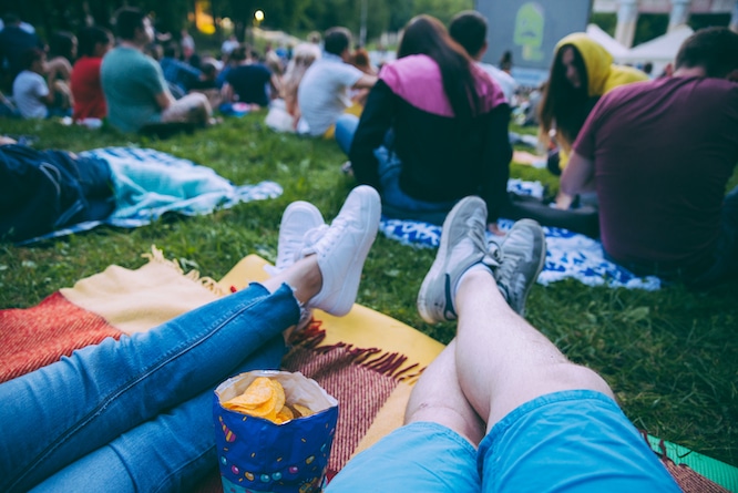 people watching movie in open air cinema in city park