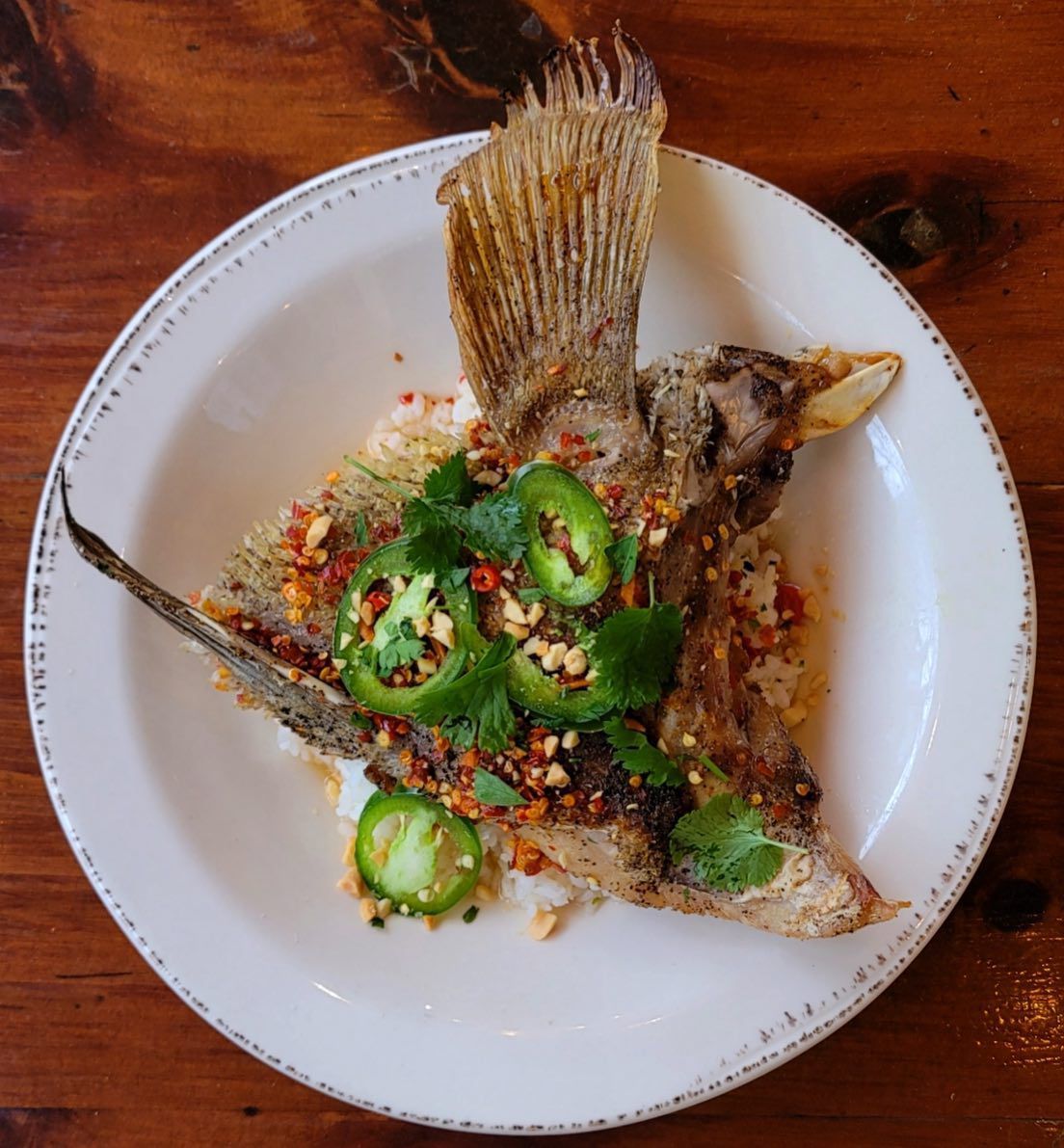 snapper collar with nuoc cham sauce sprinkled with peanuts and freshly sliced jalapenos sitting atop a bed of sushi rice from the Lawrence in Atlanta, GA. 