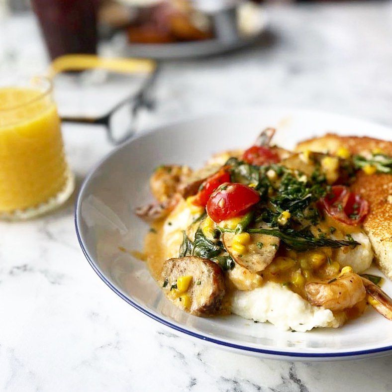 Queen City shrimp and grits with blackened shrimp sautéed with chicken sausage, fresh corn, cherry tomato, spinach, and seafood truffle butter sauce on top of creamy grits at Breakfast at Barney’s in Atlanta. 
