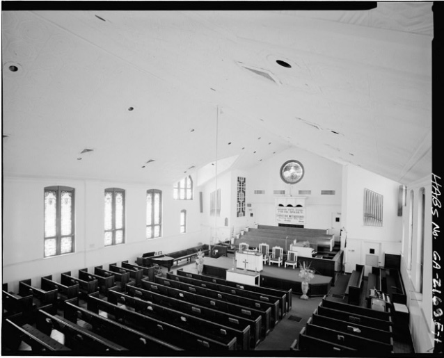 A high angle view of the pulpit, organ, and pews within the white-walled interior of a church. A high angle view of the pulpit, organ, and pews within the white-walled interior of a church.