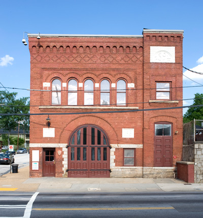 The fire station is a rectangular, red brick building with arched doors, windows, and brickwork. The fire station is a rectangular, red brick building with arched doors, windows, and brickwork.