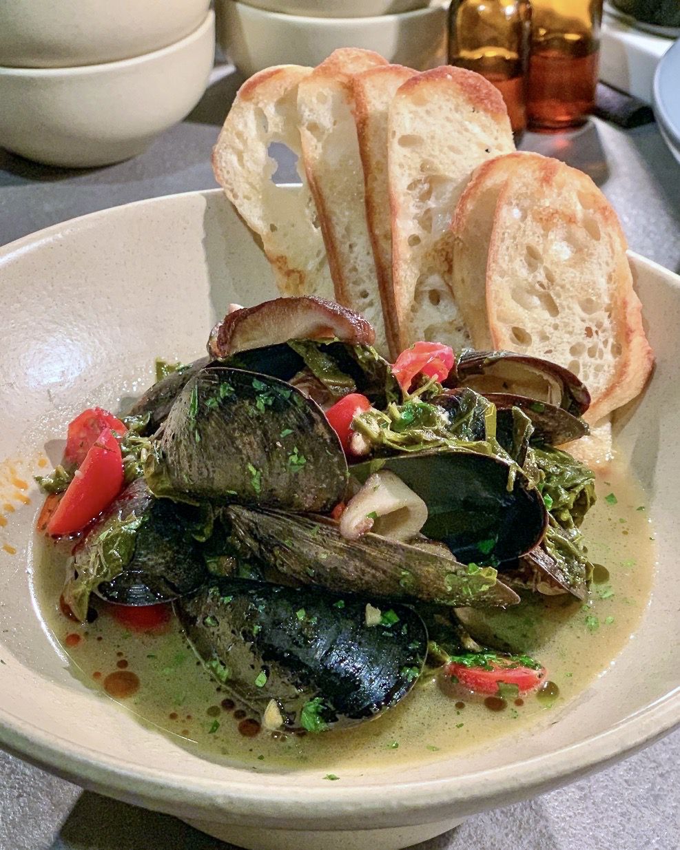 Mussels and collard greens with bacon, shiitake mushrooms, baguette slices, and grape tomatoes at Southern National in Atlanta. 