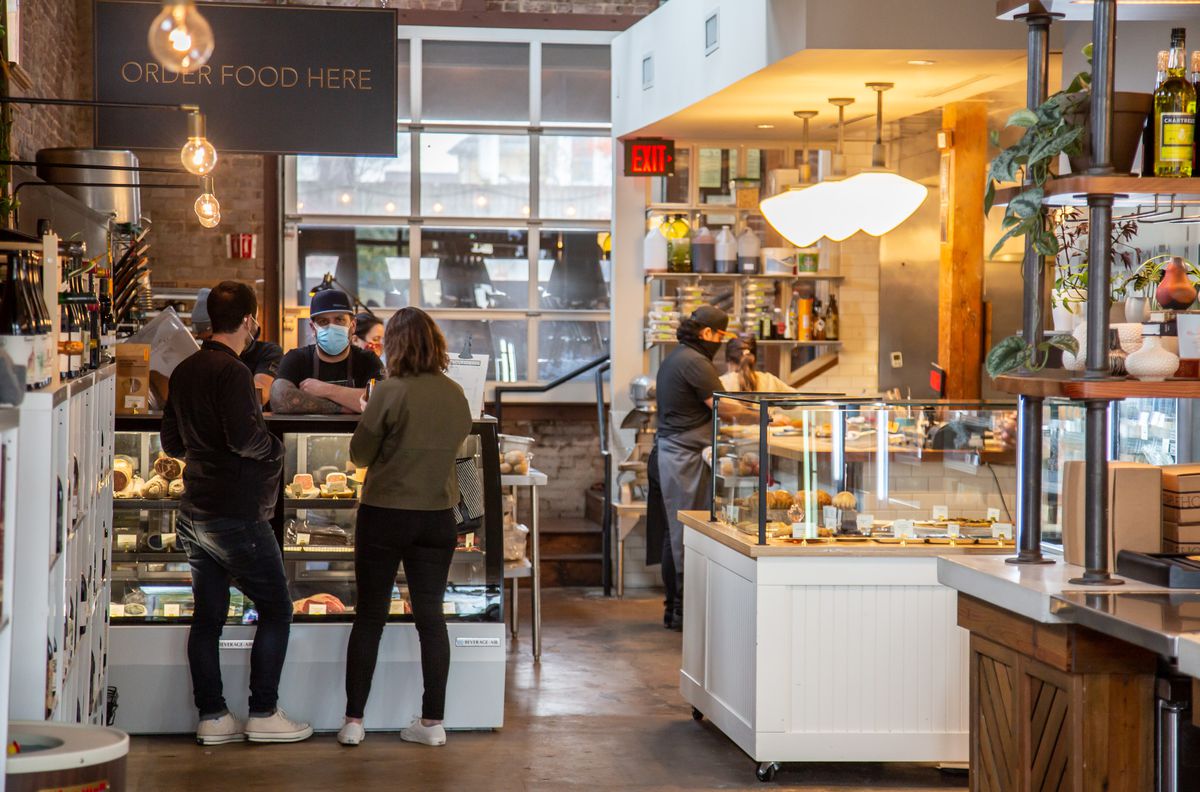 The newly opened Staplehouse market on Edgewood Avenue in Atlanta with two people ordering meats and cheese at the counter from a masked employee during the pandemic of 2020
