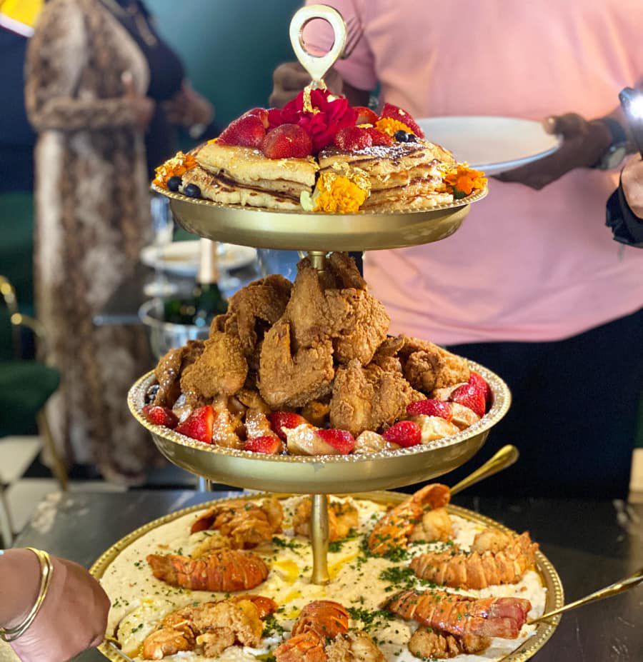Mansa Musa Tower a three-tier tray set-up with 24 karat gold pancakes, fried chicken, fried lobster and grits, 1 bottle of premium champagne at Breakfast at Barney’s in Atlanta.