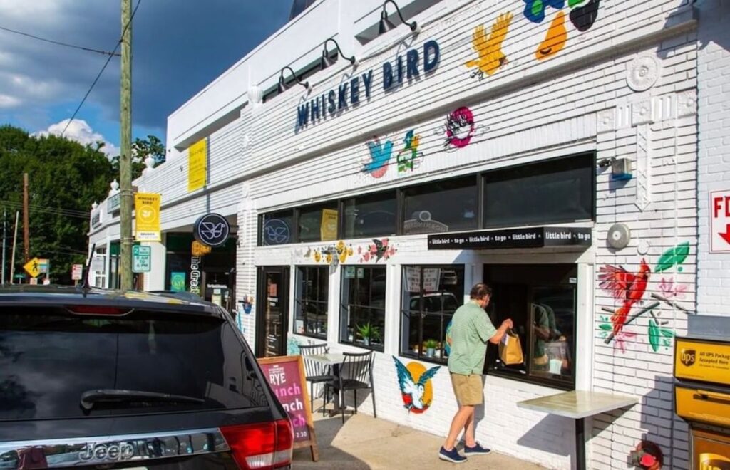 walk up window of a white restaurant covered in art